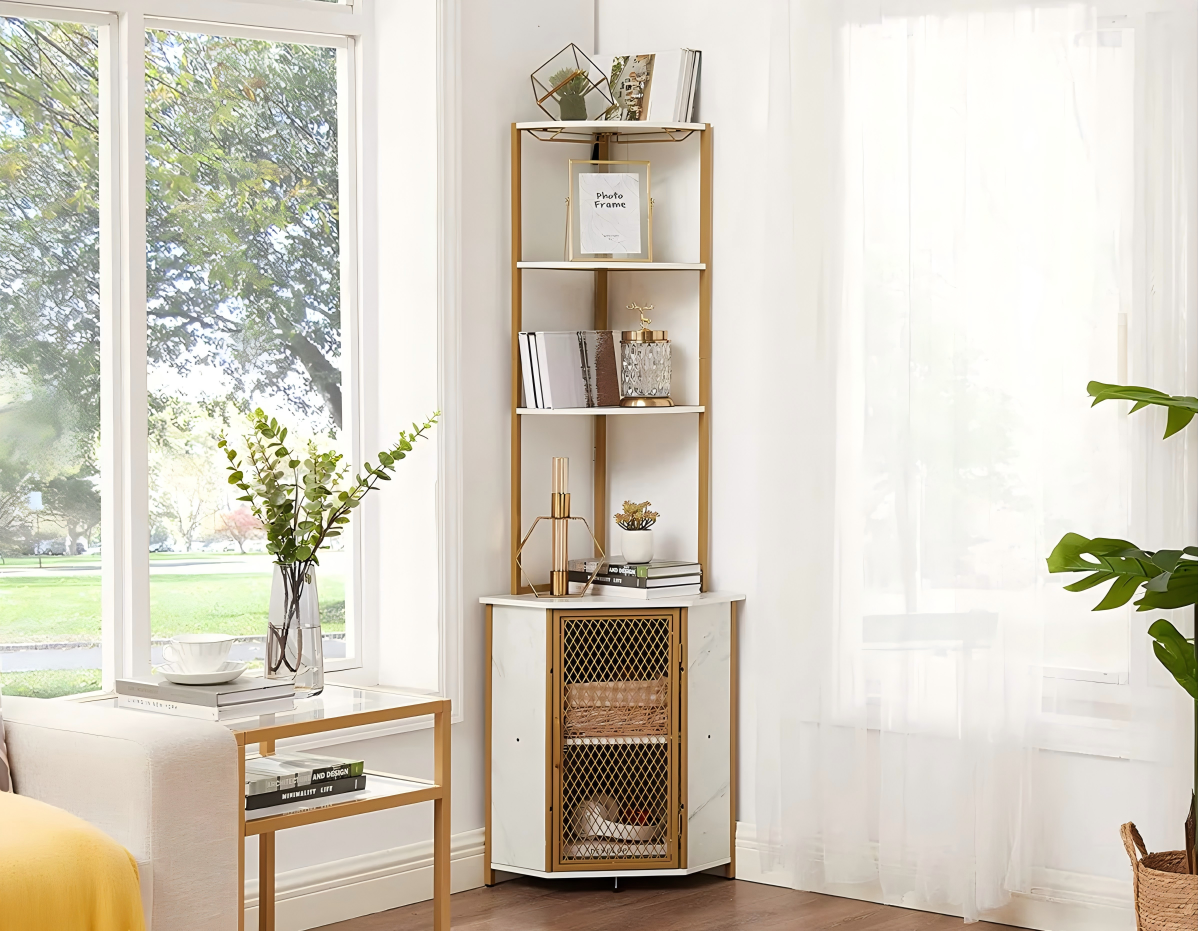 “Modern gold and white corner shelf cabinet with marble finish, styled with books, glassware, and decorative accents in a bright living room by the window.”
